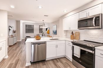 A modern kitchen with white cabinets and stainless steel appliances at Floresta, Jupiter, 33458